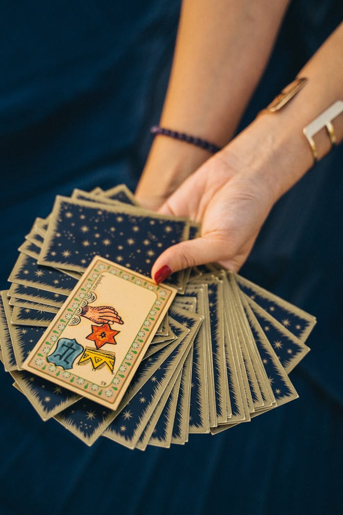 about-us Close-up of a hand holding tarot cards, symbolizing spirituality and divination.